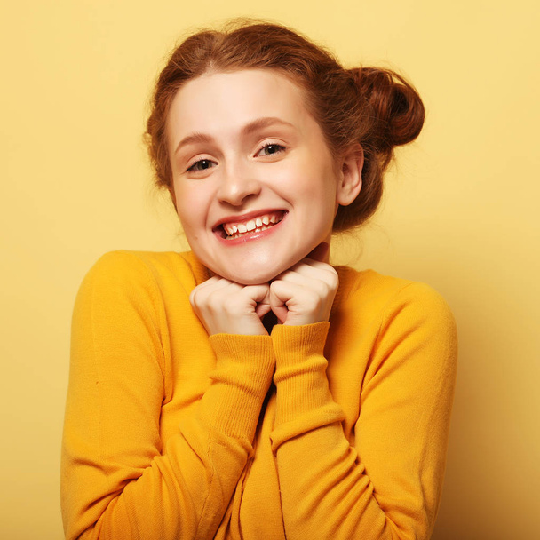 Young cute smiling redhair girl on yellow  background - Фото, зображення