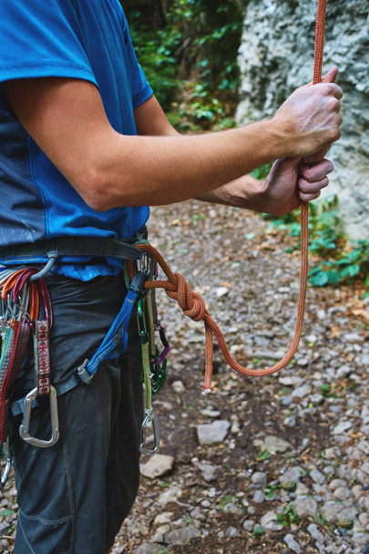 Een man verzekert klimmer via een belay apparaat. - Foto, afbeelding