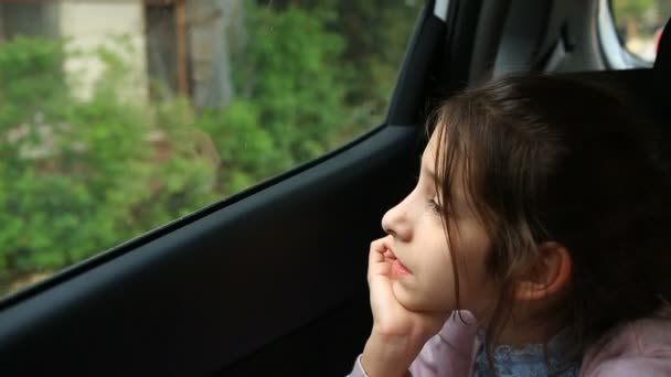Little girl bored in car - staring into space through window - great reflections of passing trees - Séquence, vidéo