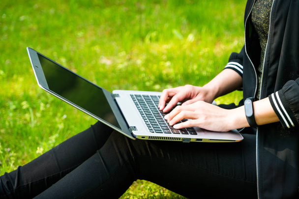 Une femme est assise sur l'herbe tout en utilisant un ordinateur portable
 - Photo, image