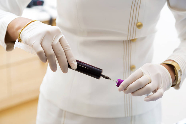 Enfermeira que tira amostra de sangue para tubo para exame de sangue
 - Foto, Imagem