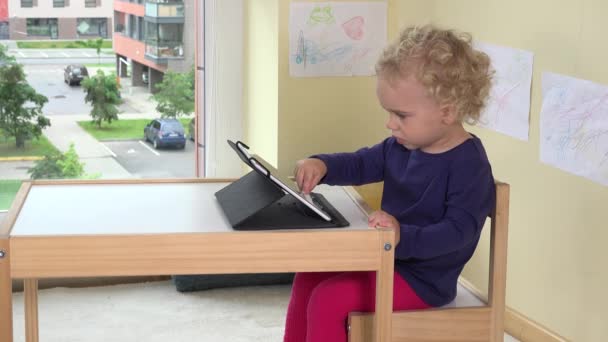 glückliches blondes Mädchen berührt Tablet-Computerbildschirm mit Finger - Filmmaterial, Video