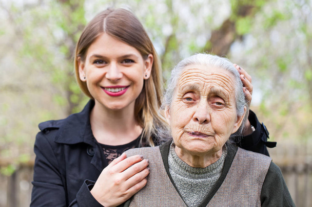 Mujer mayor con su cuidador al aire libre
 - Foto, imagen