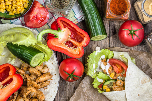 Preparing tortilla wrap, fajita mexican sandwich with meat fried in gyros spice - chicken stripes and vegetables, homemade cooking recipe - Foto, imagen