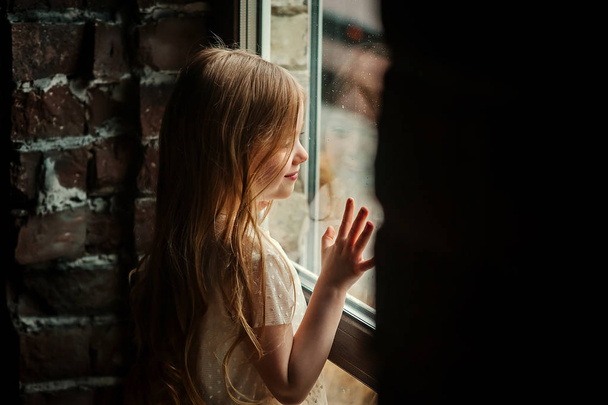 girl looking through window - Foto, afbeelding