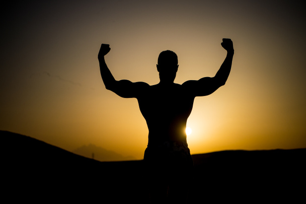夕焼け空で筋肉の男のシルエット - 写真・画像