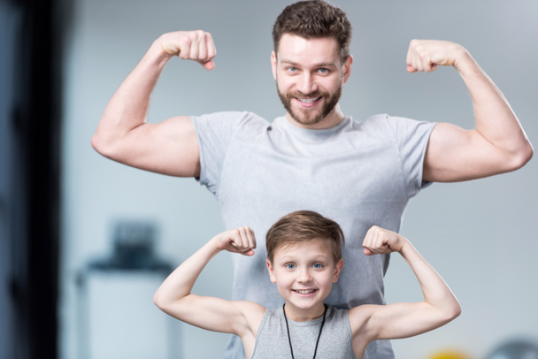 Niño con joven mostrando los músculos
  - Foto, Imagen