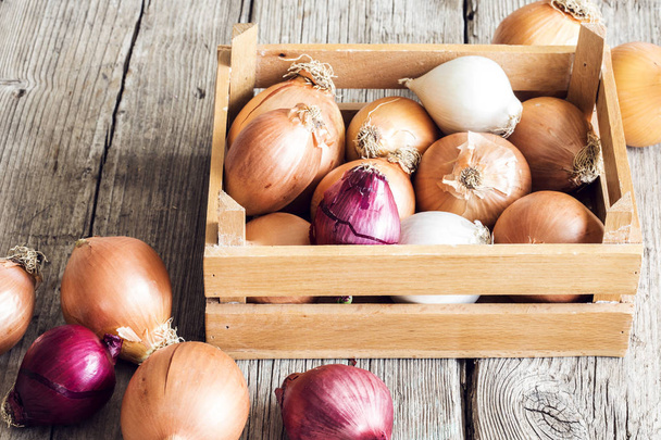 Raw onions in basket on wooden table - Photo, Image