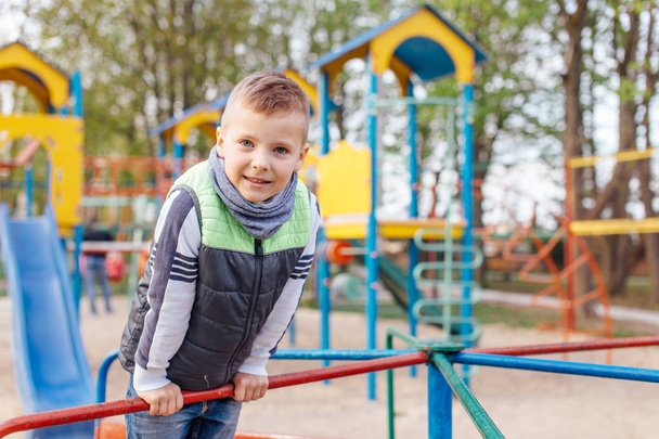 Little boy play on playground with blur park background - Fotó, kép