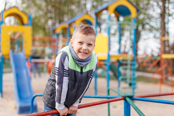 Little boy play on playground with blur park background - Фото, изображение
