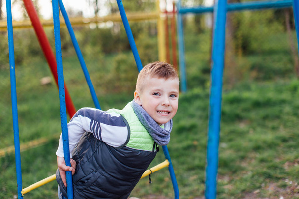 Little boy play on playground with blur park background - Fotó, kép