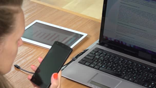 Επιχειρήσεων γυναίκα Phone εξιτήριο σε φορητό υπολογιστή με το καλώδιο usb. Κλείστε - Πλάνα, βίντεο
