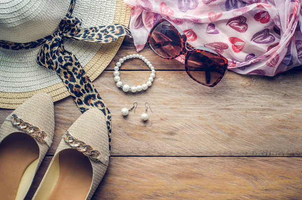 accessoires voor teenage girl op haar vakantie, hoed, stijlvolle voor zomer zonnebrillen, schoenen en kostuum op houten vloer. - Foto, afbeelding
