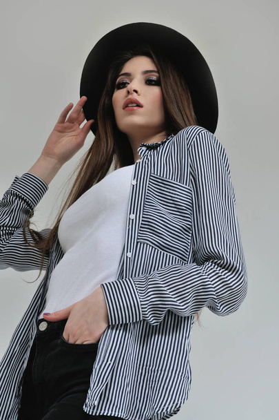 Bottom view of a girl in a black hat who is dressed in a striped - Fotó, kép