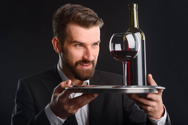 The wine is perfect. Sommelier evaluated appearance of red wine and he is satisfied with its quality. Photo of wine connoisseur on black background. - Foto, Bild