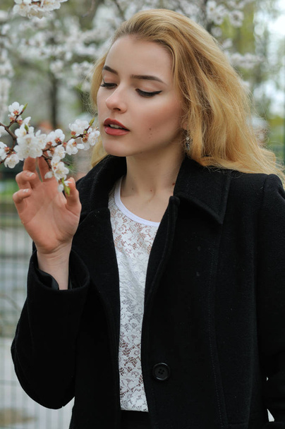 Girl enjoys the smell of flowering apricots - Zdjęcie, obraz