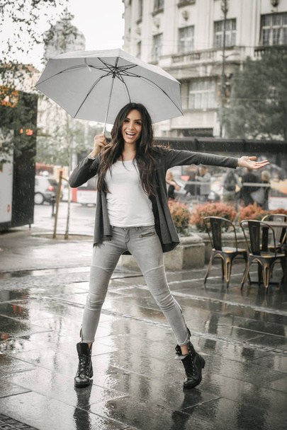 Woman dancing in the rain with umbrella, Splash in puddle - Foto, afbeelding