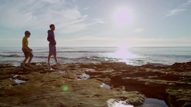 Pai e filho estão olhando para uma bela paisagem em uma praia
 - Filmagem, Vídeo