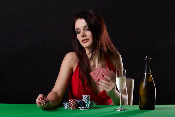 young brunette woman playing poker on black background - Foto, afbeelding