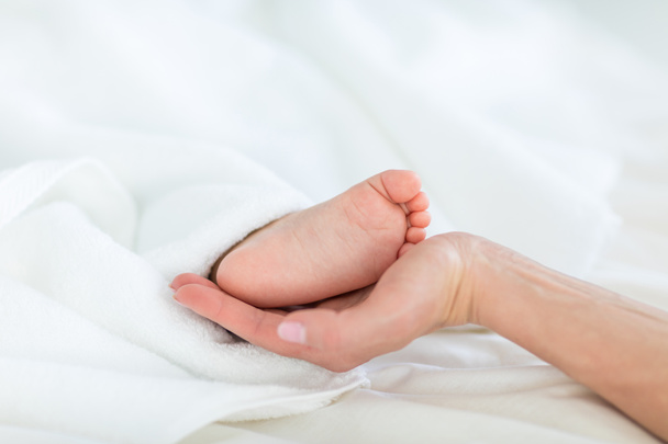 Mother holding foot of child  - Photo, Image