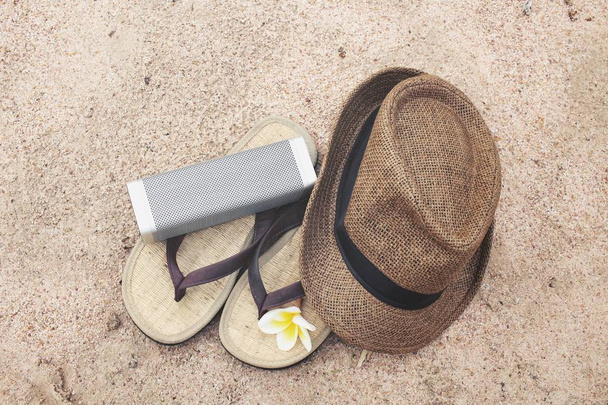 Flip flops with hat and bluetooth speaker on beach - Photo, Image