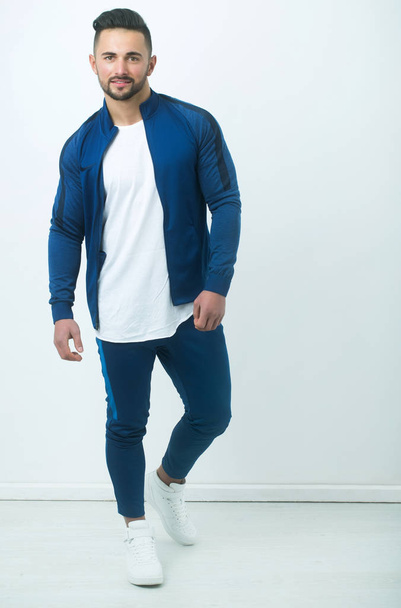 Smiling bearded man in fashionable blue sportswear and athletic footwear - Valokuva, kuva