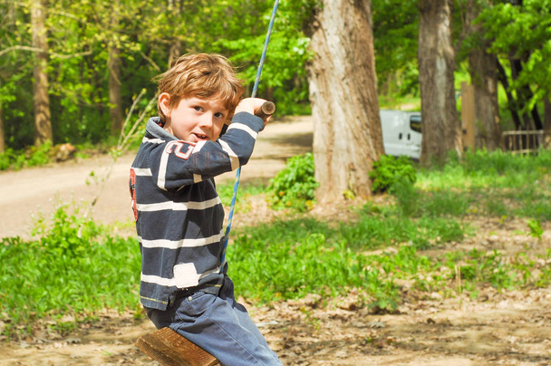A boy is riding a rope swing - Photo, Image