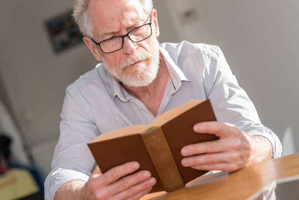 Mature man reading a book - Zdjęcie, obraz