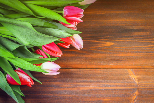 Bouquet of pink tulips on brown wooden background. Top view, copy space. Happy mother's day. - Foto, imagen