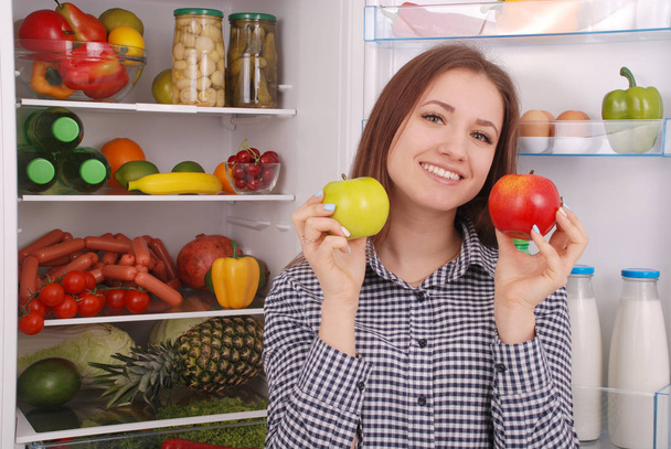 Beautiful young girl near the Fridge with healthy food. - Foto, afbeelding