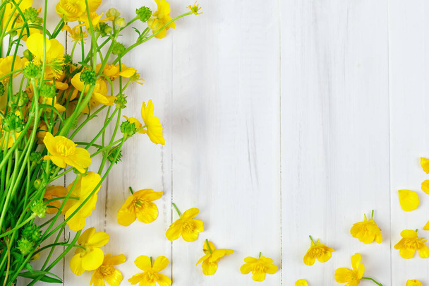 Beautiful yellow Buttercup bouquet lying on white wooden boards. - 写真・画像