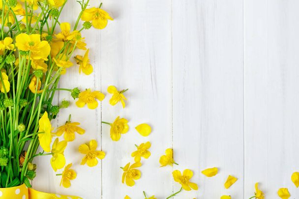 Beautiful yellow Buttercup bouquet lying on white wooden boards. - 写真・画像