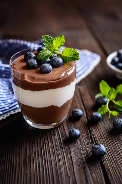 Шоколадний і ванільний десерт з маскарпоне, вкритий чорницею
 - Фото, зображення