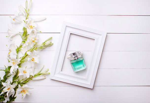 Çiçekler lily ve parfüm beyaz bir arka plan üzerinde beyaz bir çerçeve içinde - Fotoğraf, Görsel
