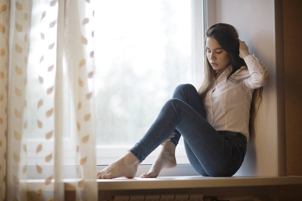 teenage girl sitting on windowsill - Photo, Image