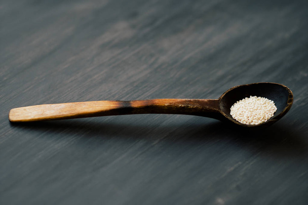 Un cucchiaio di semi in un cucchiaio di legno naturale in stile rustico sullo sfondo di un albero naturale strutturato di colore scuro. Con un filo per la firma
 - Foto, immagini