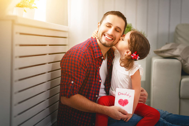 Isänpäivä. Onnellinen perhe tytär suudella isää ja antaa onnittelukortin
 - Valokuva, kuva