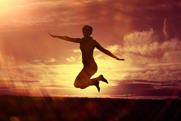 woman jumping against sunset sky - Foto, afbeelding