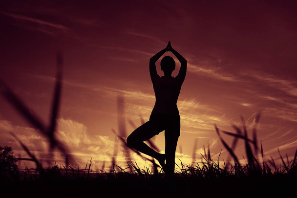 Žena, která dělá jógu proti západu slunce na obloze - Fotografie, Obrázek