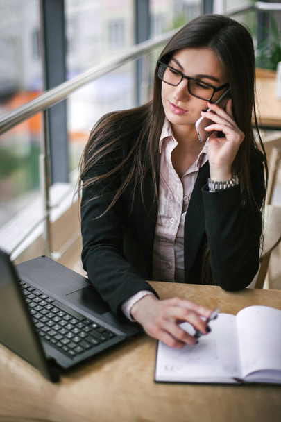 Business lady sitting in white office and taking calls at table - Photo, image