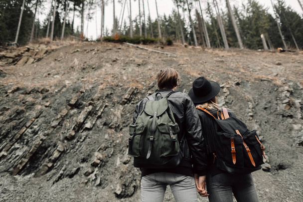 The couple are traveling. Boy and girl with backpacks travel. A man and a woman near the cliff. The couple are back. Travel - Foto, afbeelding