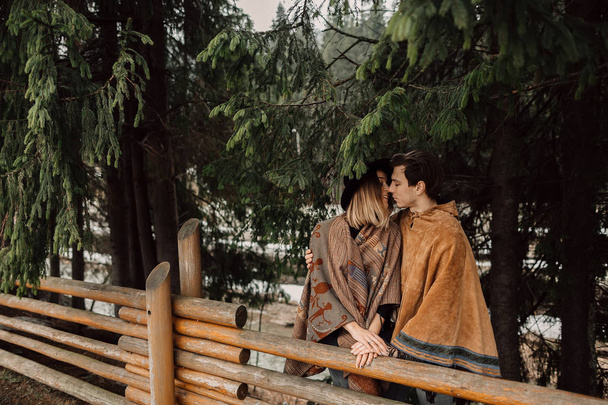 ポンチョのカップル。男はポンチョ、ポンチョに身を包んだ女性を着ています。森の中の愛情のあるカップル - 写真・画像