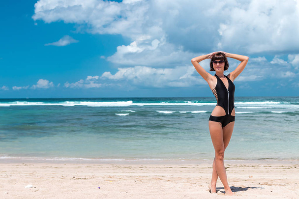 Strandvakantie. Gelukkige vrouw genieten van zonnige dag op het strand. Open armen, vrijheid, geluk en zaligheid. Tropische concept, Bali eiland. - Foto, afbeelding