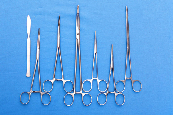 Хирургические инструменты и инструменты, включая скальпели, щипцы и пинцет, расположенные на столе для операции - Фото, изображение