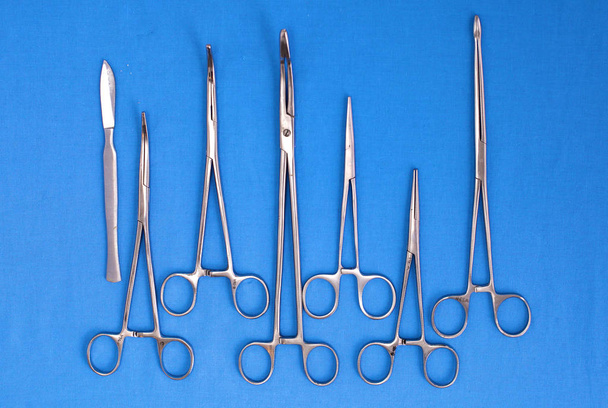 Chirurgische Instrumente und Werkzeuge wie Skalpelle, Pinzetten und Pinzetten auf einem Tisch für eine Operation angeordnet - Foto, Bild