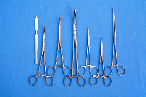 хірургічні інструменти та інструменти, включаючи скальпи, щипці та пінцет, розташовані на столі для хірургічного втручання
 - Фото, зображення