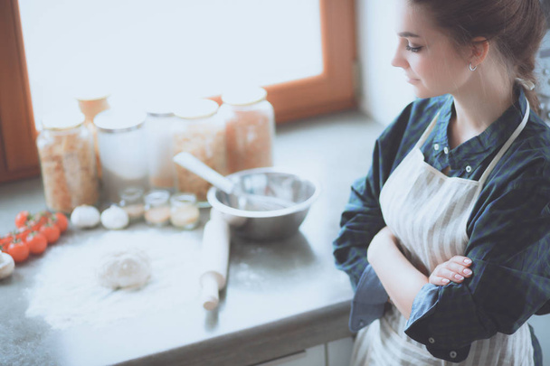 Beautiful woman cooking cake in kitchen standing near desk - Foto, Bild
