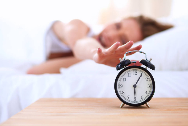 Young sleeping woman and alarm clock in bedroom at home - Fotó, kép