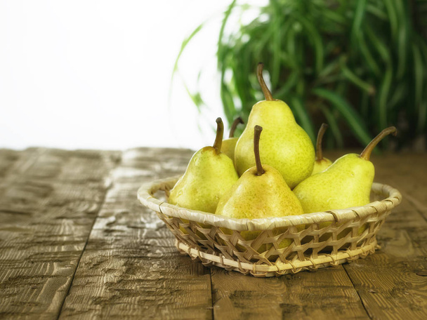 Wicker basket with ripe pears on a wooden table. - Photo, Image