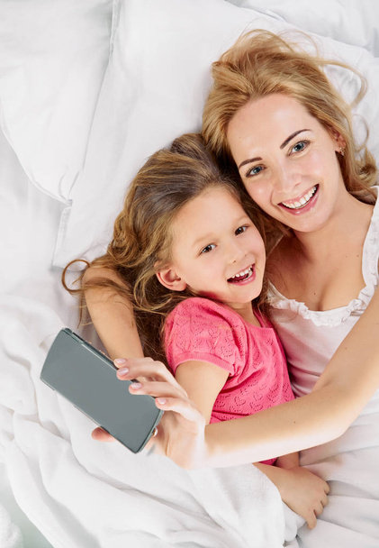 Mother daughter. selfie in white bed - Фото, изображение